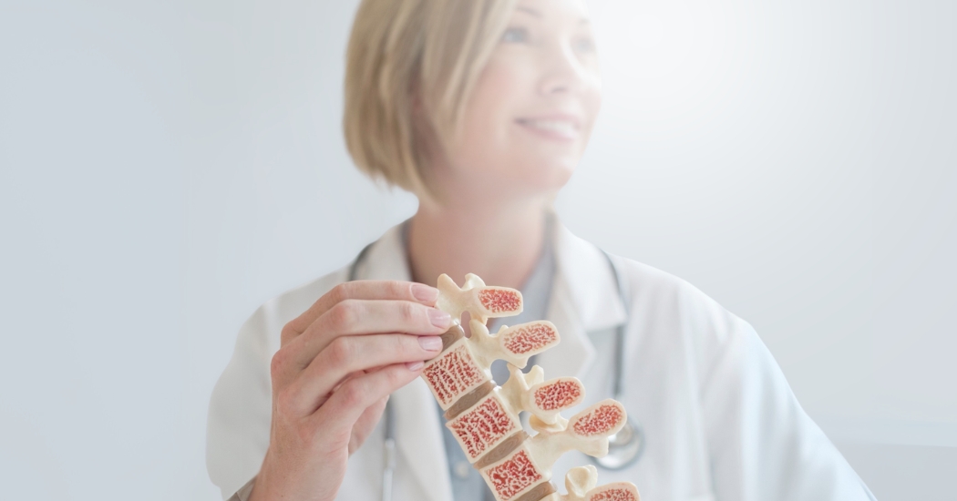 Μια γιατρός κρατάει ένα ομοίωμα σπονδυλικής στήλης.