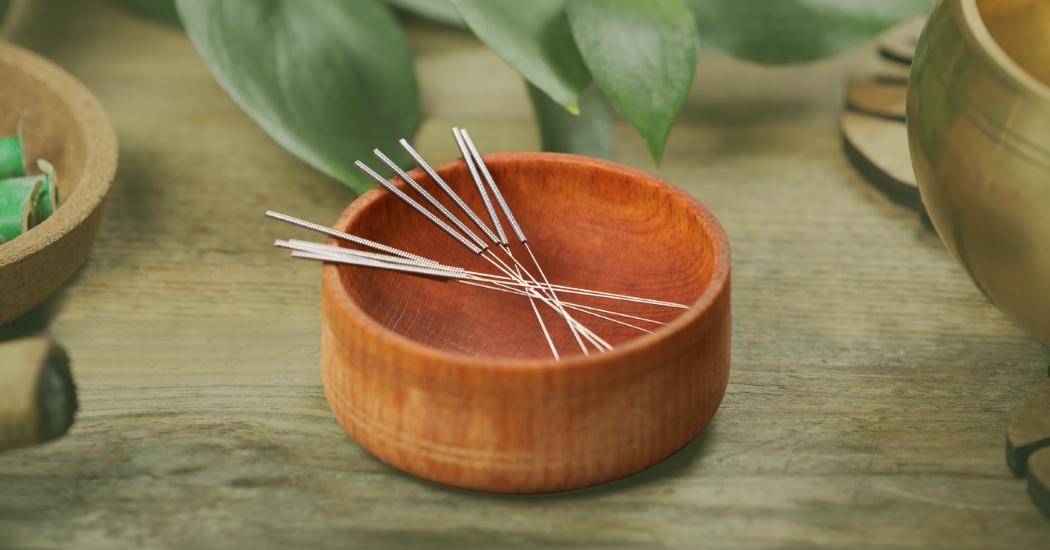 Βελόνες για βελονισμό σε ένα πήλινο σκεύος και πρασινάδα γύρω γύρω.