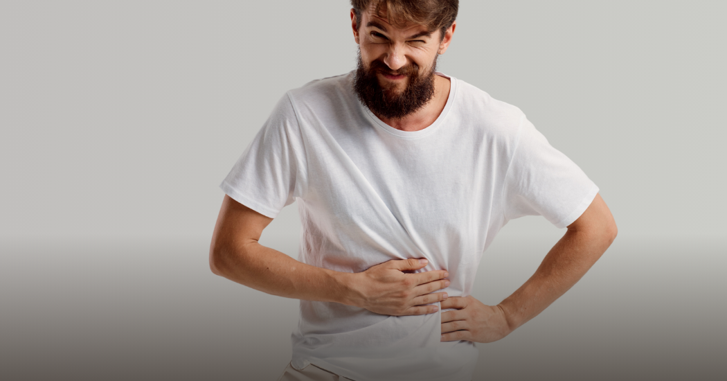 Ένας άνδρας που πιάνει το στομάχι του με δυσφορία.
