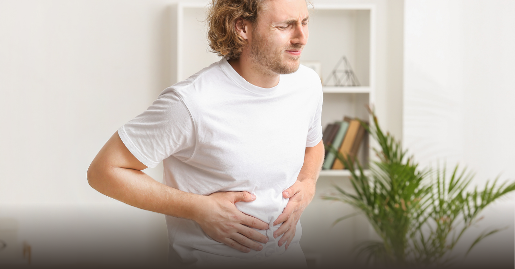 Ένας άνδρας πιάνει την κοιλιά του από τον πόνο.